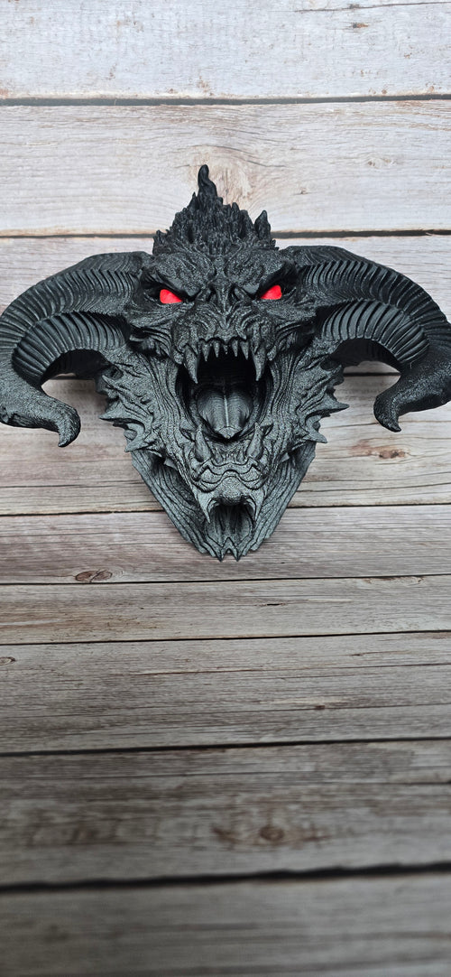 Front view of the Ashen Hornlord demon skull wall art showing its symmetrical horns, open mouth, long fangs and red eye details.