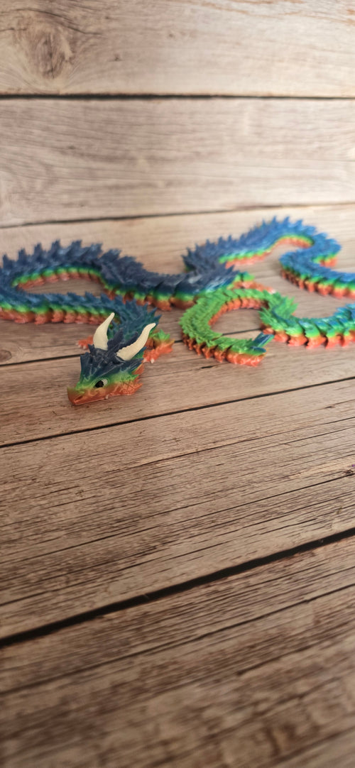 Long articulated dragon figurine in blue, green and coral with pale curved horns and a flexible segmented serpentine body.