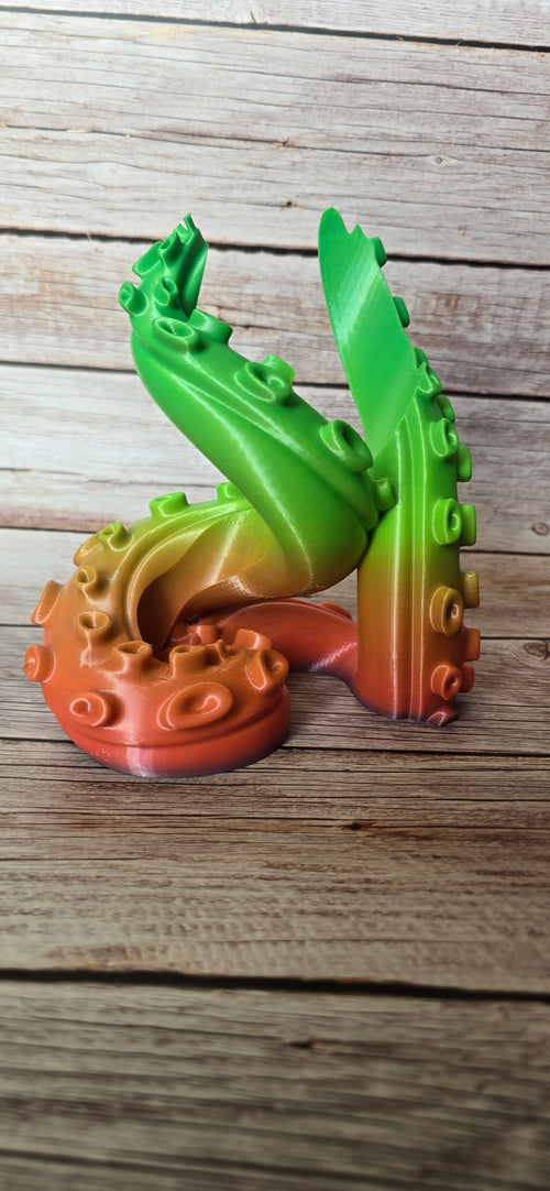 Side view of the Verdant Grasp bottle holder showing several tall curling green tentacles rising from coral and orange bases.