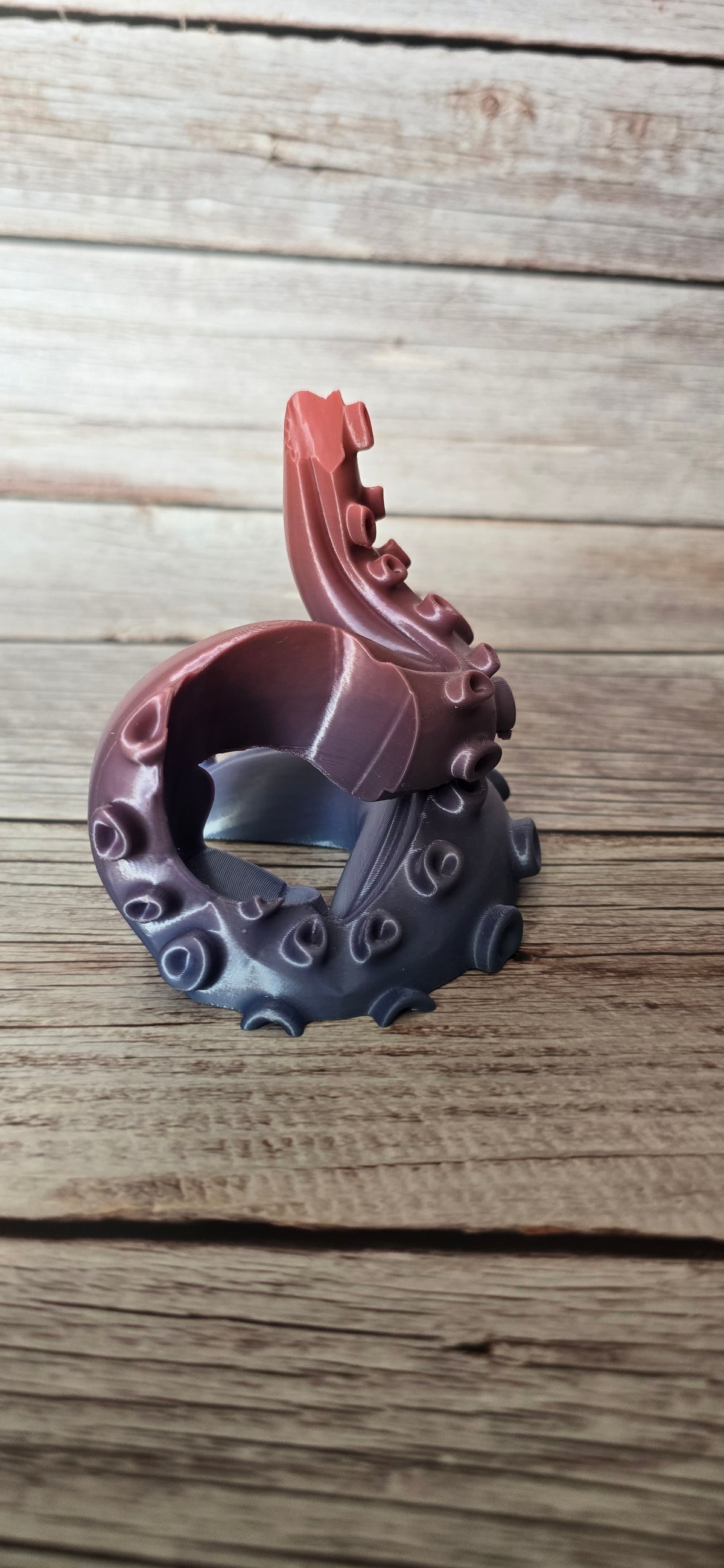 Side view of an empty 3D printed PS5 tentacle controller stand with a curled arm and copper-to-blue colour transition.